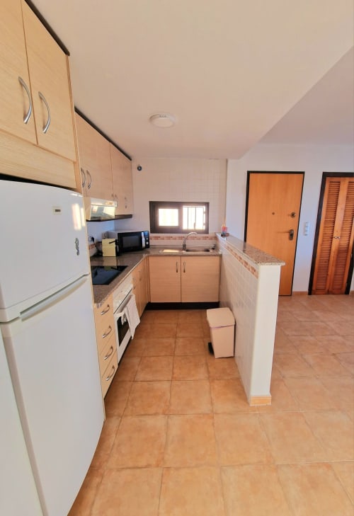Cocina moderna con muebles de madera, encimera de granito y suelo de baldosas de barro en alquiler vacacional de Águilas