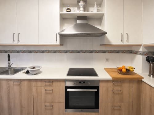 Cocina moderna en la casa rural Alborada, Baiona con armarios blancos, encimera y campana de acero inoxidable, armarios inferiores de madera