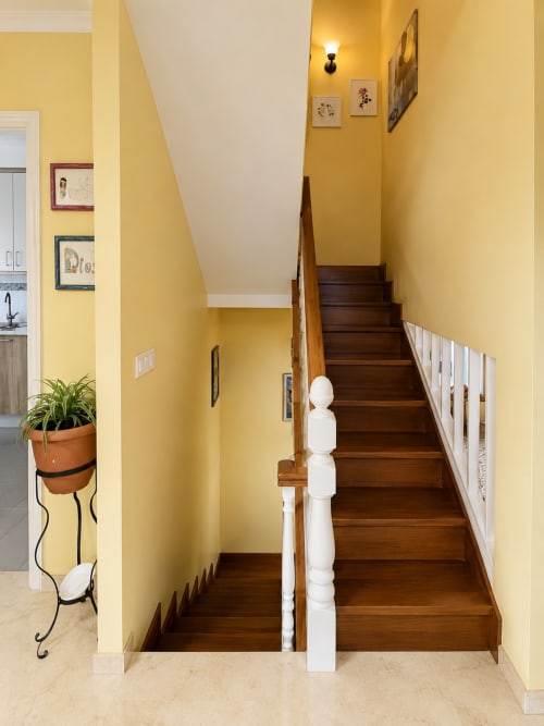 Escalera luminosa amarillo brillante con barandillas blancas y peldaños de madera oscura en la casa de campo Alborada, Baiona