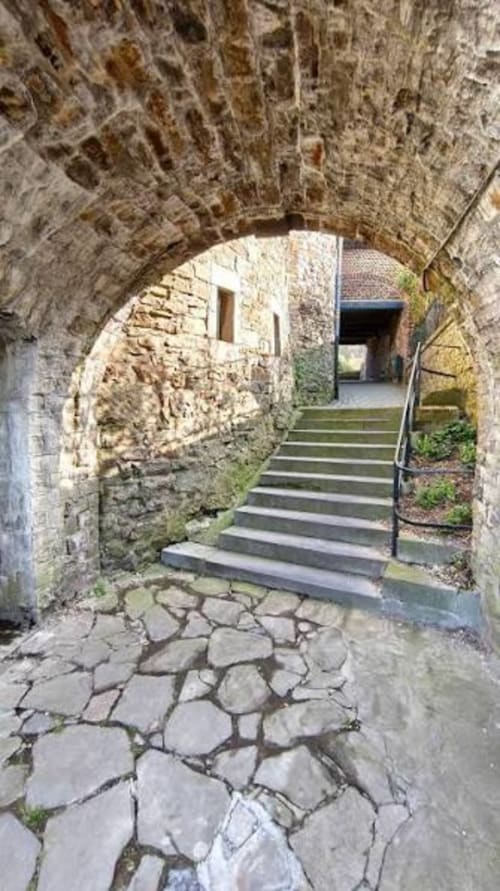 Stone archway entrance at Villa Bianca B&B in Mortroux Dalhem with cobblestone path and stairs leading inside
