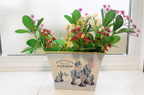 Flores decorativas en macetas con flores rojas y amarillas en el alféizar blanco de la cabaña Holibai en Baiona
