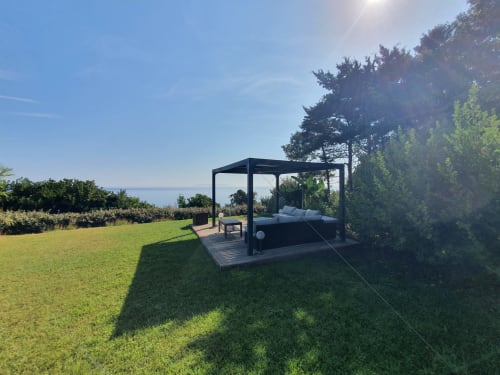 Pergola noire moderne avec chaises longues sur terrasse en bois surplombant la mer Méditerranée, Villa EOLE, Centuri Corse