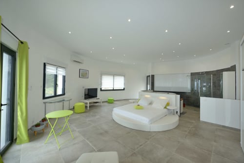 Chambre de villa moderne avec lit rond, touches vert citron et salle de bains attenante à La Conciergerie du Cap Corse, Centuri