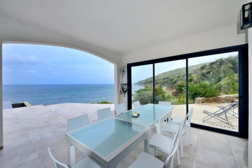 Élégante salle à manger de villa moderne avec vue mer sur la Méditerranée, table en verre et chaises blanches sur la terrasse à Cap