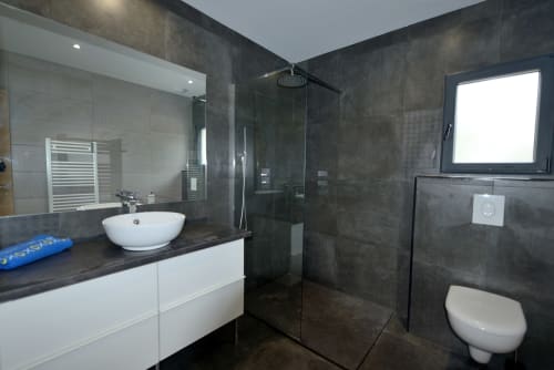 Salle de bain moderne de la Villa EOLE à La Conciergerie du Cap Corse avec douche à l'italienne, vasque blanche et toilettes