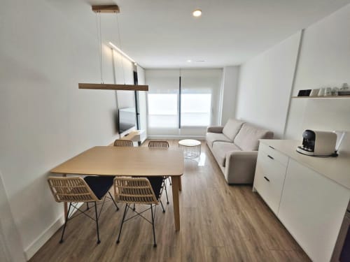 Moderno apartamento diáfano en BR Silgar Sanxenxo con comedor, sofá, cocina, TV y luz natural