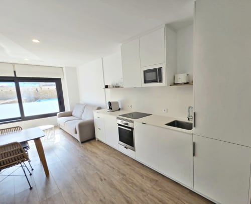Cocina abierta moderna y sala de estar en apartamento BR Silgar en Sanxenxo con muebles blancos y vistas costeras