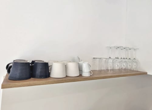 Estantería de madera en el apartamento BR SILGAR Sanxenxo exhibiendo teteras azules, jarras blancas y cristalería transparente