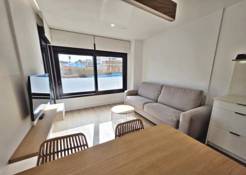 Sala de estar moderna en BR Silgar Sanxenxo con sofá gris, mesa de comedor y vistas a la terraza