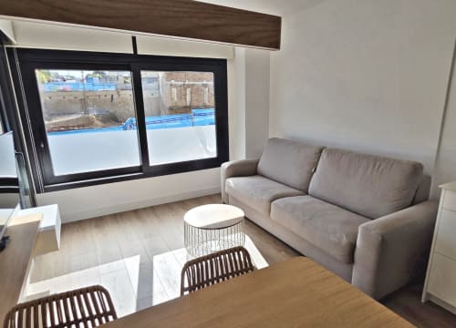 Sala moderna del apartamento en BR Silgar, Sanxenxo con sofá gris, mesa de madera y vistas a la terraza