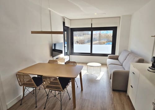 Apartamento moderno en BR Silgar Sanxenxo con comedor, sofá gris, TV y vistas a terraza con paisaje nevado