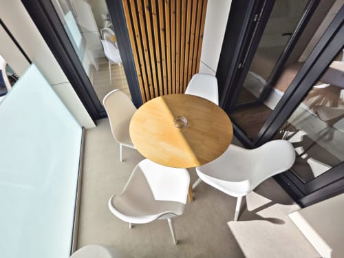 Zona de comedor moderno en BR Silgar Sanxenxo con mesa de madera redonda y sillas blancas en la terraza