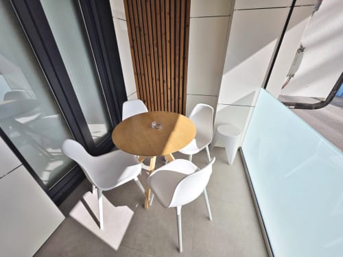 Zona de comedor en la terraza de BR Silgar Sanxenxo con mesa redonda de madera y sillas blancas con vistas a la costa