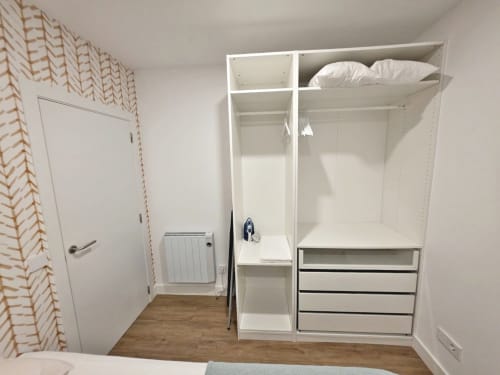 Armario blanco moderno con almacenamiento en el apartamento BR Silgar, Sanxenxo. Armario empotrado con perchero y cajones.