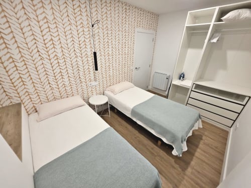 Moderno dormitorio compartido en apartamento BR Silgar Sanxenxo con camas gemelas, papel pintado estampado y armario empotrado
