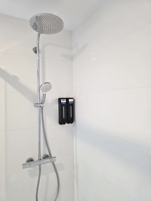 Sistema de ducha moderno con alcachofa de lluvia y mampara de mano en el apartamento BR Silgar de Sanxenxo