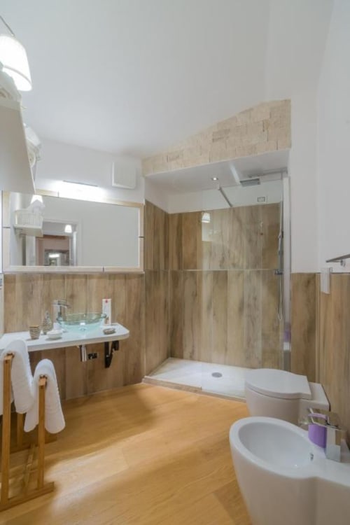 Bagno moderno a Country Domos Ozieri con rivestimenti in legno, ampia cabina doccia e pavimentazione in legno massello