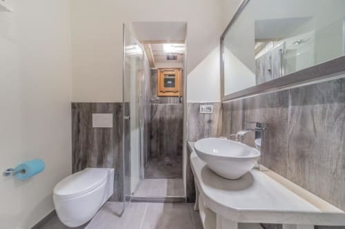 Bagno moderno nel Country Domos B&B con water, lavabo cilindrico, piastrelle effetto legno grigio e doccia in vetro