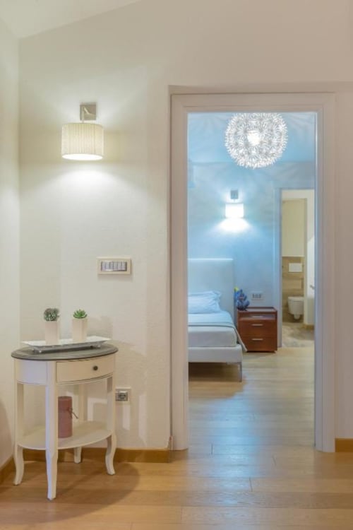 Elegante ingresso del Country Domos B&B a Ozieri con arredi color crema, pavimenti in legno e vista sulla camera da letto principale
