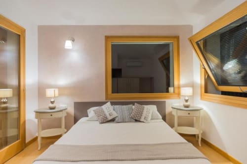 Camera da letto moderna con stile rustico presso Country Domos a Ozieri: letto matrimoniale, comodini in legno e grande specchio