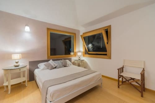 Camera luminosa con letto matrimoniale, specchi in legno, pavimenti in parquet e zona living presso Country Domos a Ozieri
