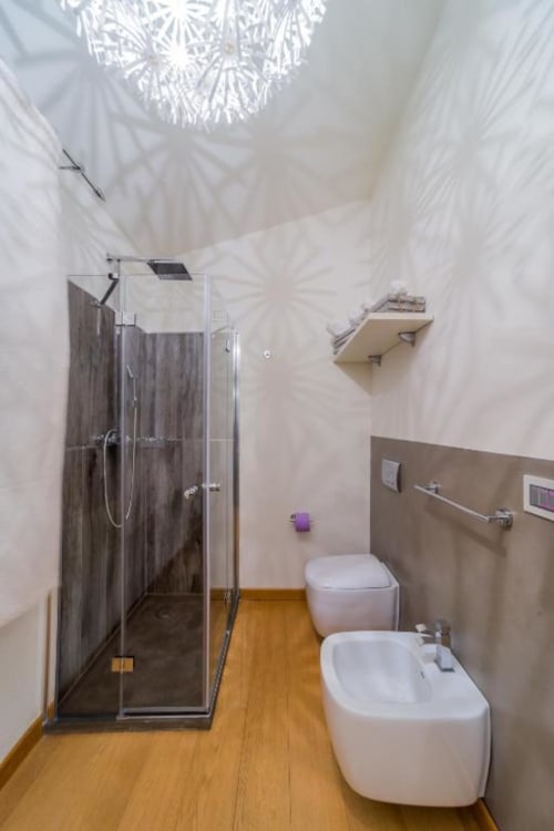 Bagno moderno con doccia in vetro, bidet e wc bianchi, pavimenti in legno nell'appartamento Country Domos, Ozieri Italia