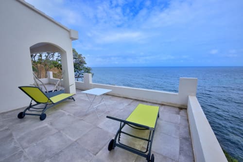 Terrasse en bord de mer de la Villa EOLE à Centuri, Corse avec transats vert citron surplombant la Méditerranée