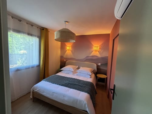Chambre douillette du gîte Les 3 Volcans à Clermont-Ferrand avec éclairage chaleureux, vue sur le jardin et mobilier moderne