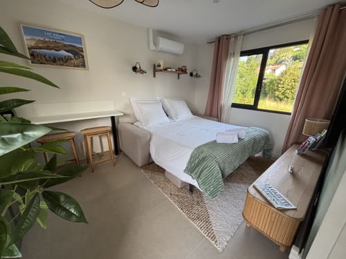 Chambre moderne à la résidence Les 3 Volcans à Clermont-Ferrand avec lit, bureau, plantes et vue sur le jardin