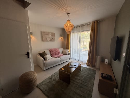 Salon moderne du gîte aux Résidence Les 3 Volcans à Clermont-Ferrand, canapé crème, table bois, vue sur jardin