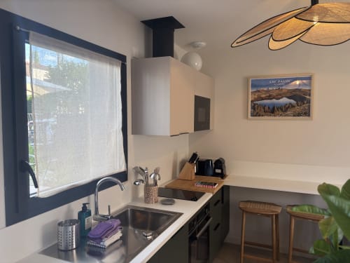Cuisine moderne du gîte Les 3 Volcans à Clermont-Ferrand, avec vue sur jardin, évier, cuisinière et tabourets en bois