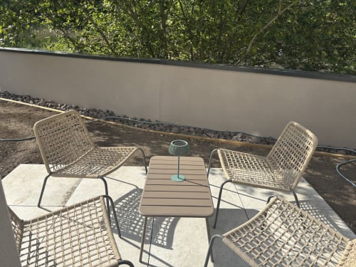 Coin détente du jardin à la Résidence Les 3 Volcans à Clermont-Ferrand avec chaises en osier et petite table entourées de verdure