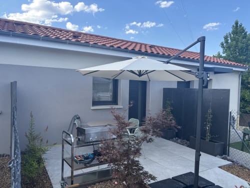 Terrasse de cottage moderne à la Résidence Les 3 Volcans, Clermont-Ferrand avec parasol suspendu, mobilier et vue sur le jardin