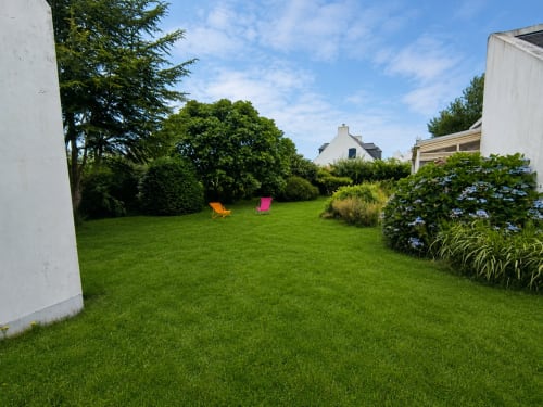 Jardin spacieux de la maison Lannivrec à Locmaria, Belle-Île-en-Mer avec pelouse soignée et chaises longues colorées