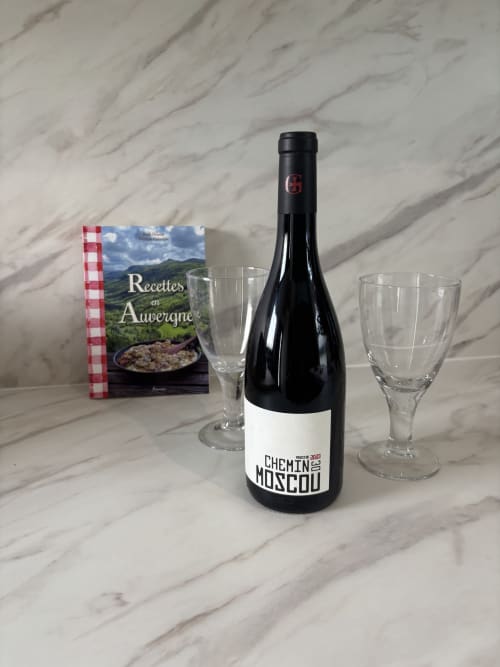 Bouteille de vin Chemin Moscou avec verres et livre de recettes d'Auvergne sur surface en marbre à la Résidence Les 3 Volcans,