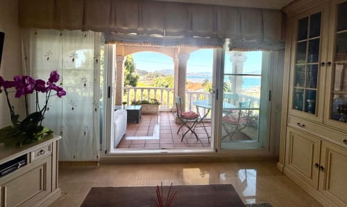 Interior elegante de cabaña costera con vistas al mar, orquídeas púrpuras y terraza con vistas a Baiona, España