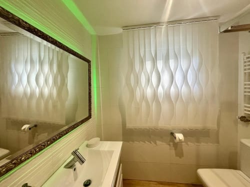 Baño moderno con azulejos texturizados ondulantes, espejo ornamental y iluminación ambiental verde en la casa rural Serenidade de Baiona