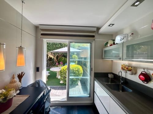 Cocina moderna con vistas al mar en la casa de Baiona, con encimeras negras, armarios blancos y puertas de cristal que se abren a