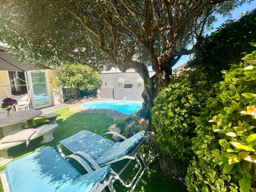 Jardín de la casa de campo de Baiona con piscina, tumbonas bajo árbol frondoso y terraza con vistas al mar
