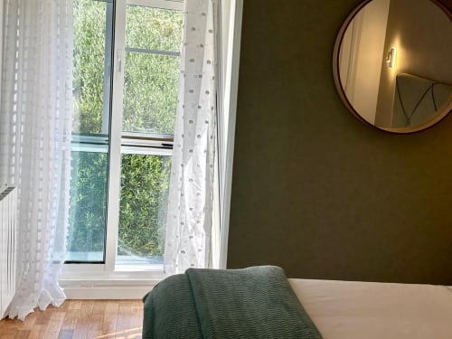 Dormitorio de la casita Serenidade en Baiona con vistas al mar, espejo redondo y puertas francesas hacia el paisaje verde