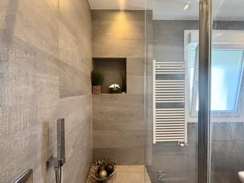 Baño moderno con ducha a ras de suelo, toallero calefactable y servicios spa en la casa Serenidade de Baiona