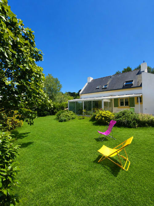 Jardin de cottage avec chaises longues colorées face à la Maison Lannivrec à Locmaria, Belle-Île-en-Mer, sous un ciel bleu dégagé