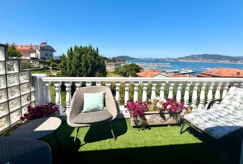 Terraza de la cabaña Serenidade en Baiona con vistas al mar, silla de mimbre, flores y paisaje costero