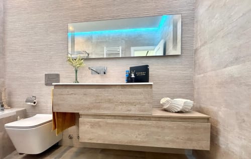 Baño moderno en la casa Serenidade, Baiona con espejo iluminado, tocador de madera, inodoro blanco y baldosas contemporáneas