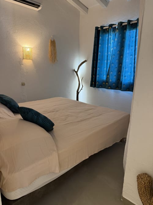 Chambre moderne de la villa Residence Fium Del Cavo en Corse avec lit blanc, rideaux bleus et décor épuré