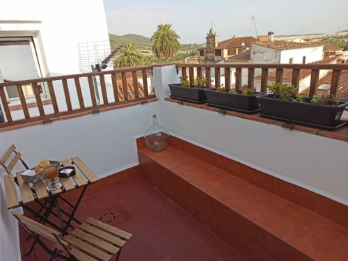 Terraza en la azotea del hotel Mirador Medieval en Cáceres con baldosas de terracota, barandillas de madera, macetas y vistas panorámicas