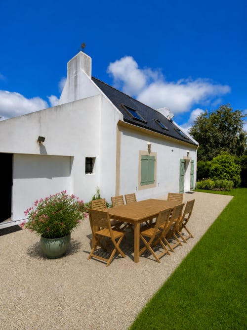 Charmant cottage blanc moderne avec terrasse-jardin, table en bois, fleurs roses et volets verts à Maison Lannivrec Belle Île