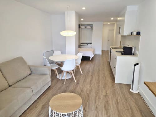Zona de estar moderna en apartamento de BR Silgar Sanxenxo con mesa de comedor, sofá, cocina e iluminación colgante luminosa