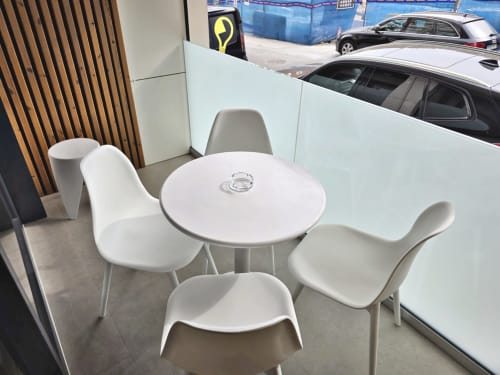 Moderna zona de estar blanca con mesa redonda en el apartamento BR Silgar de Sanxenxo, España, con vistas a coches aparcados a través del cristal