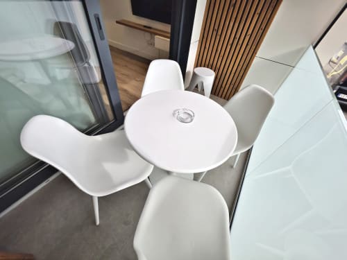 Mesa comedor redonda blanca moderna con dos sillas en apartamento BR Silgar, Sanxenxo, con puerta de tablillas de madera visible